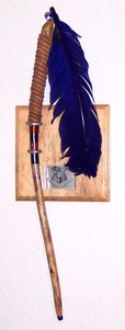 A curved wand with a feather on the handle hanging on a wall