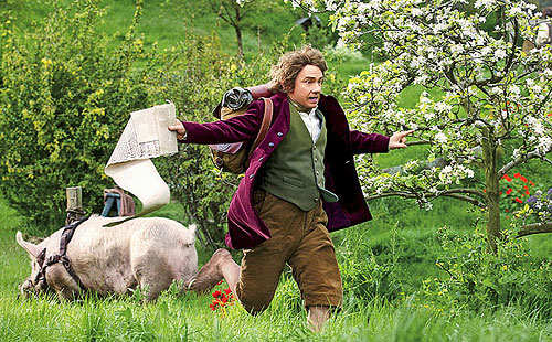 Bilbo running through a field, past a pig, with a long piece of parchment trailing after him